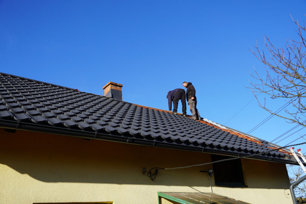 Pracovníci na střeše dělají novou krytinu